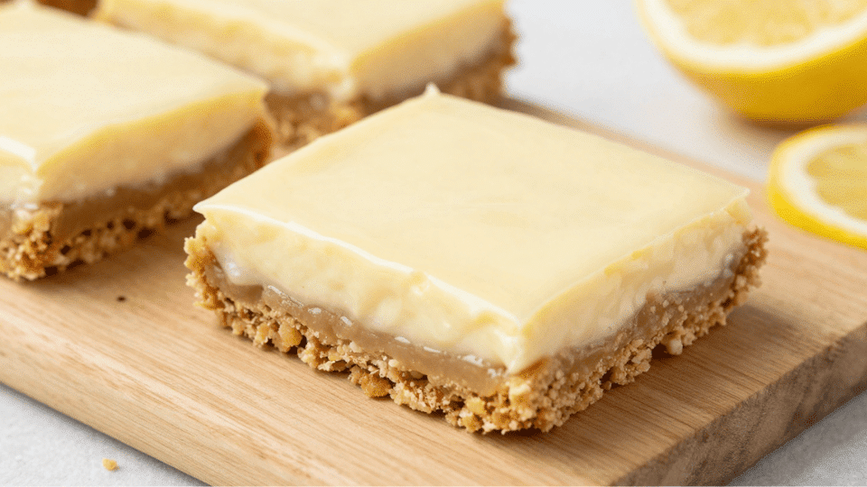 Gluten-free lemon bars with graham cracker crust, creamy lemon filling, garnished with fresh lemon slices.